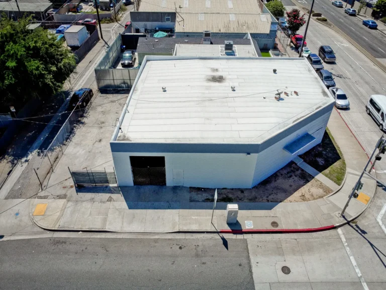 Aerial view of a white industrial building with street frontage and parking
