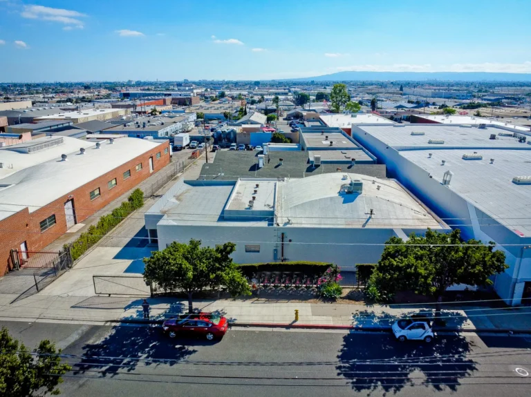 Aerial view of a Southern California industrial district with warehouse rooftops and distant hills