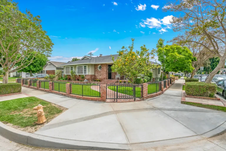 Single-story home with a wrought-iron fence on a tree-lined residential street