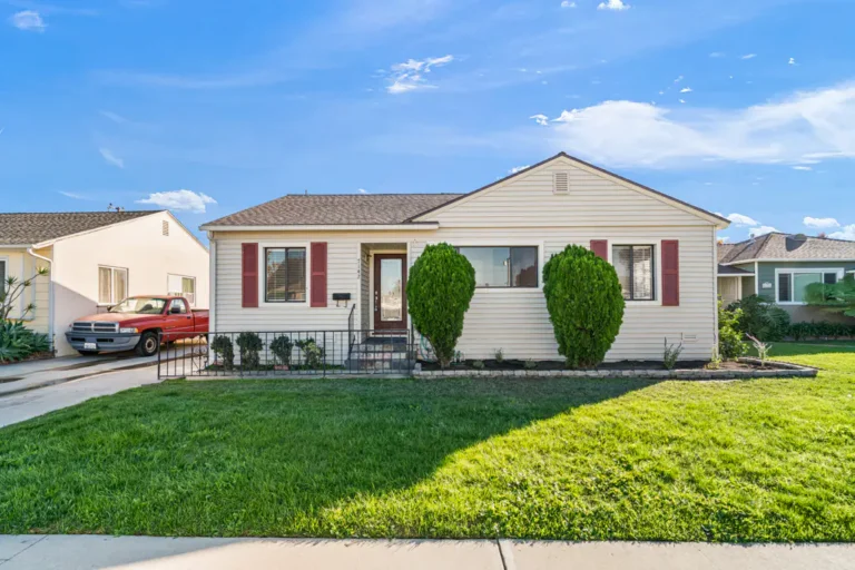 White single-story home with red shutters and a manicured lawn