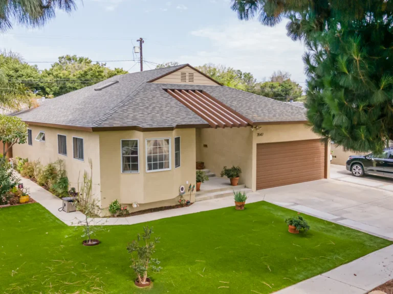 Stucco home with a tiled roof, lawn and two-car garage